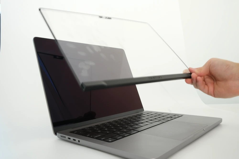 A user lifting up Magic Screen from the MacBook to show the smudges on it and none on the MacBook