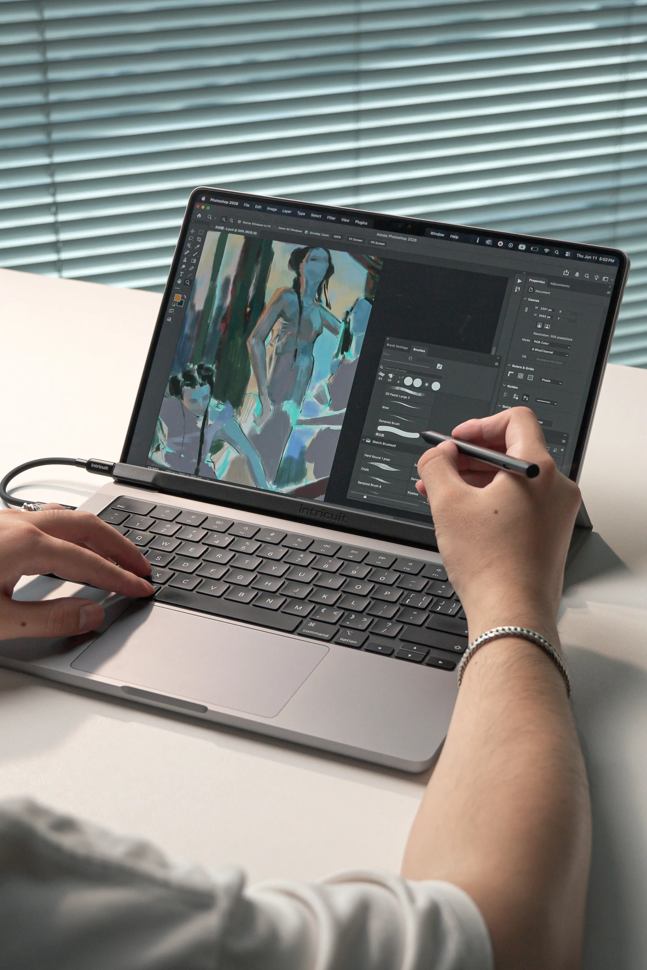 A creator using a stylus to paint in Adobe Photoshop on a touchscreen MacBook equipped with the Intricuit Magic Screen overlay.